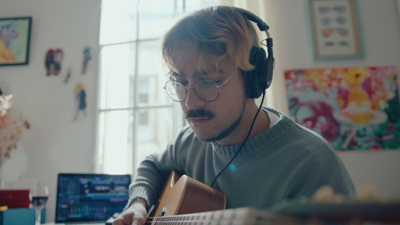 Musician in Headphones Picking Chords on the Guitar