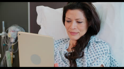 paciente femenina en una cama de hospital usando una tableta digital