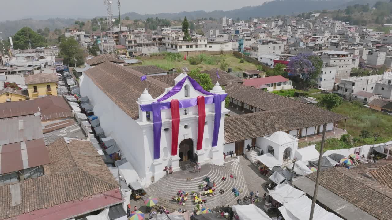 imágenes aéreas de una iglesia en chichicastenango cubierta con colores de pascua que se mueven con el viento con vendedores en los escalones