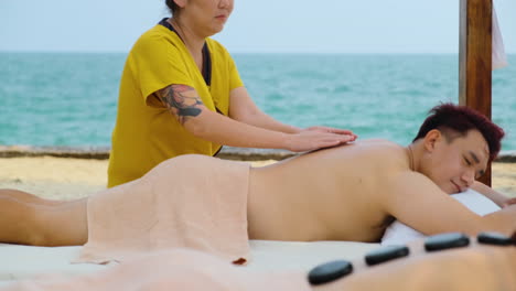 pareja recibiendo un masaje en la playa