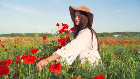 Mujer-Caucásica-Con-Sombrero-Recoge-Amapolas-Rojas-Y-Huele-Flores-En-Un-Campo-Pintoresco,-Pan-De-Cierre-Manual