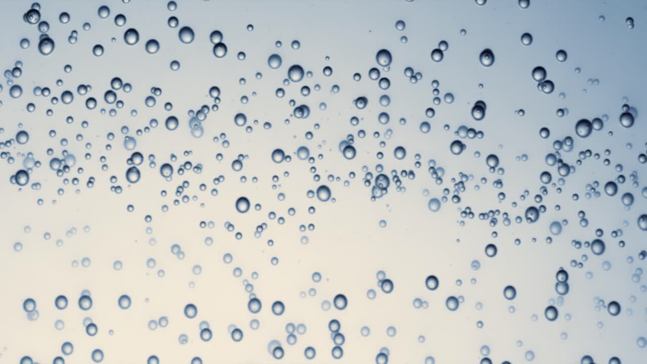 Many water bubbles in blue water close up, abstract water wave with bubbles in slow motion.