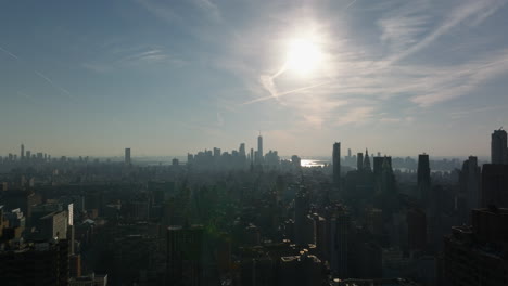 Aerial-panoramic-shot-of-large-city.-Silhouettes-of-downtown-skyscrapers-against-sun.-Manhattan,-New-York-City,-USA