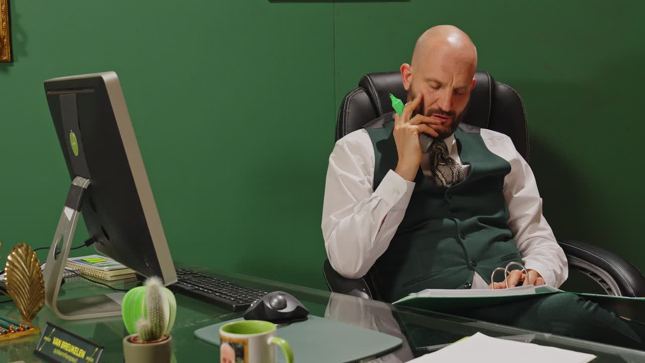 짜증난 매니저는 사무실에서 일하면서 파일에 메모를 표시하고 한숨을 쉬고 있습니다.