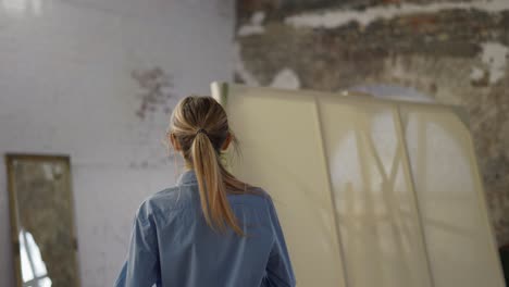 young woman wearing apron to start painting in workshop