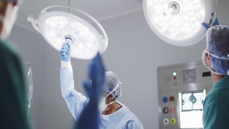 video de diversos asistentes quirúrgicos masculinos y femeninos ajustando las luces en el quirófano