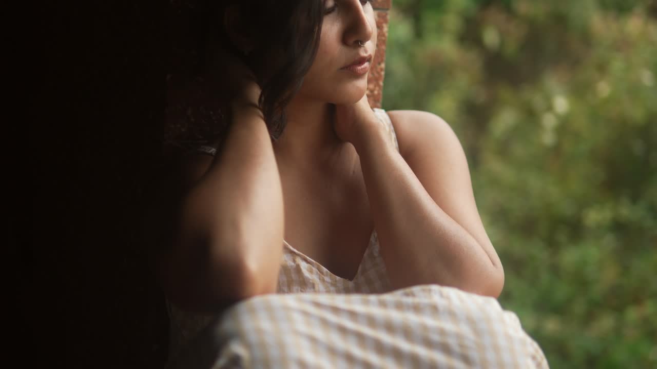 아름다운 젊은 여성이 시골 환경에서 머리카락을 조정합니다. 자연빛으로 포착된 부드럽고 친밀한 순간입니다.