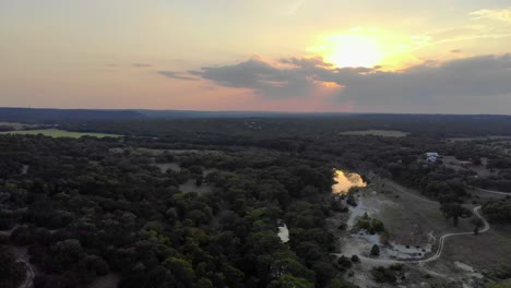 aerial - pulling back from sunset showing hill country with fields, trees, - river