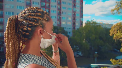 niña de raza mixta con trenzas en el cabello y máscara facial durante el brote del virus covid-19 y parada de cuarentena afuera