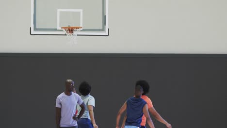 Diverse-male-basketball-players-blocking-and-shooting-ball-during-game-at-indoor-court,-slow-motion