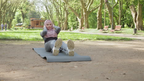 woman in hijab doing sit-ups in a park