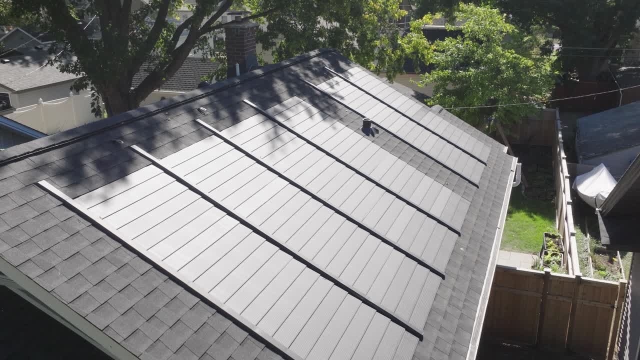 잎이 많은 교외의 주거 지붕에 설치된 태양 전지판의 공중 전망입니다.