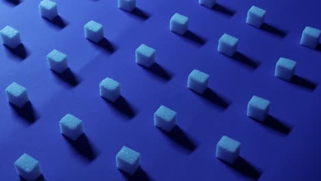 vista panorámica lenta de derecha a izquierda de un fondo cúbico único con cubos de azúcar blanco dispuestos en filas sobre un fondo azul oscuro, efecto 3d