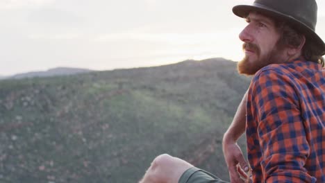 Bearded-caucasian-male-survivalist-admiring-the-view-from-mountain-peak-in-wilderness