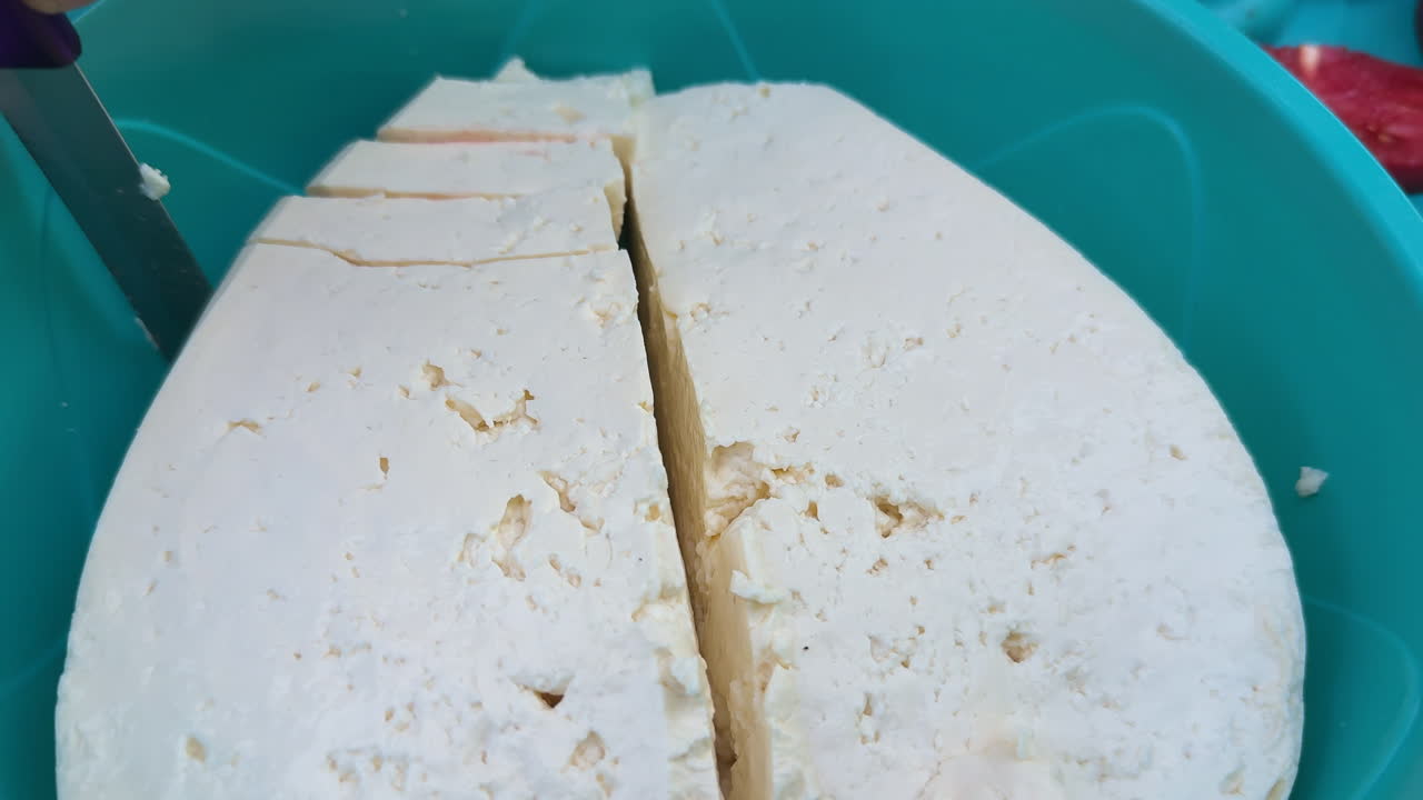 Hand cutting fresh organic cheese in close up view showing detailed texture