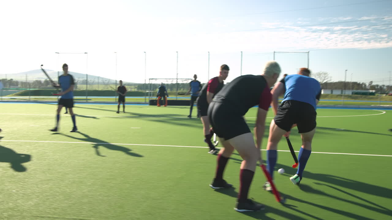 Playing field hockey, men competing in intense match on outdoor field