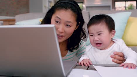 mother with crying baby using laptop