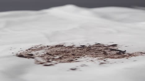 primer plano de una mancha marrón en tela blanca