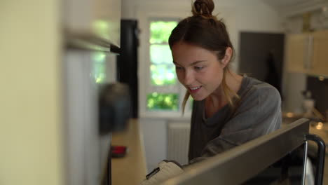 Young-Woman-Taking-Freshly-Baked-Bread-Out-of-Oven