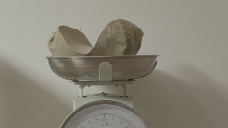 putting a piece of clay for weighting on a scales in ceramics studio