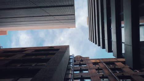 looking up between tall buildings to the blue sky above in the city - low angle shot