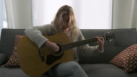 attractive young blonde woman playing an acoustic guitar