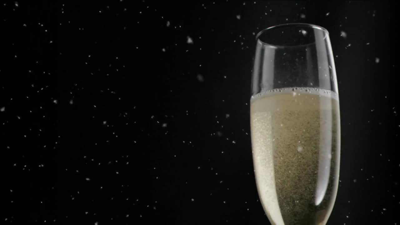 Animazione di particelle bianche che fluttuano su bicchiere di champagne su sfondo nero.