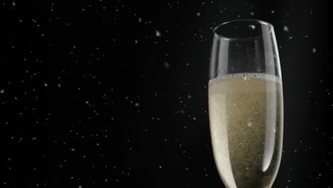 animation of white specks floating over glass of champagne on black background