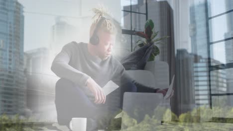 animación de iconos estadísticos flotando sobre un hombre albino afroamericano que trabaja en una computadora portátil en casa