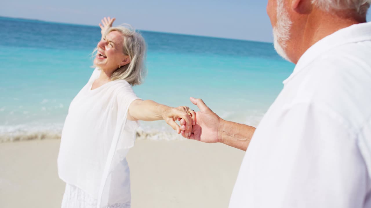 행복 한 은퇴 한 부부 가 열대 해변 에서 함께 춤추고 있다
