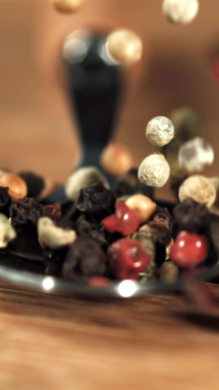 Mixed Peppercorns Falling in Slow Motion onto a Spoon