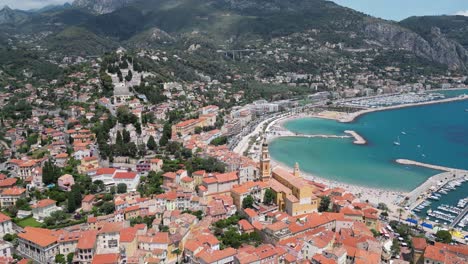 Beach,-Marina-and-Saint-Michel-Basilica-at-the-seaside-town-of-Menton-Southern-France,-Aerial-dolly-out-shot