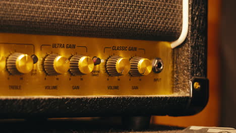 close-up of plugging a jack into a guitar amplifier and turning up the volume knob, live concert show, playing music on guitar tube amplifier.