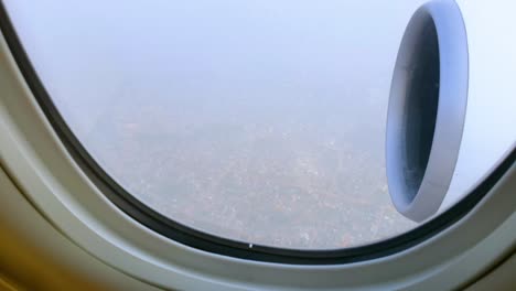 view through airplane window over the city during landing on cloudy day