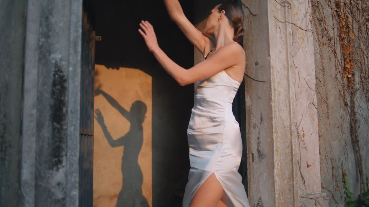 아름다운 소녀는 벽에 그림자를 만드는 빛을 움직인다. 손으로 춤을 추는 여자