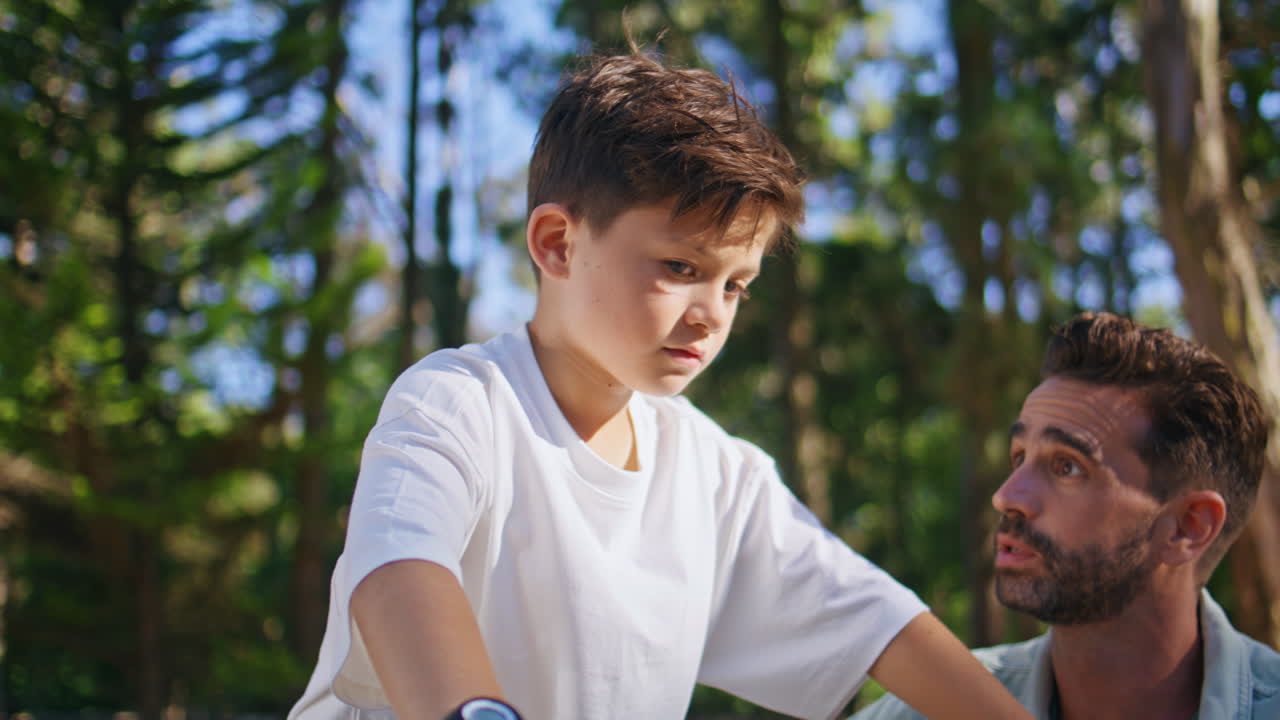 Caring father talking kid explaining bike ride at sunshine greenery park closeup