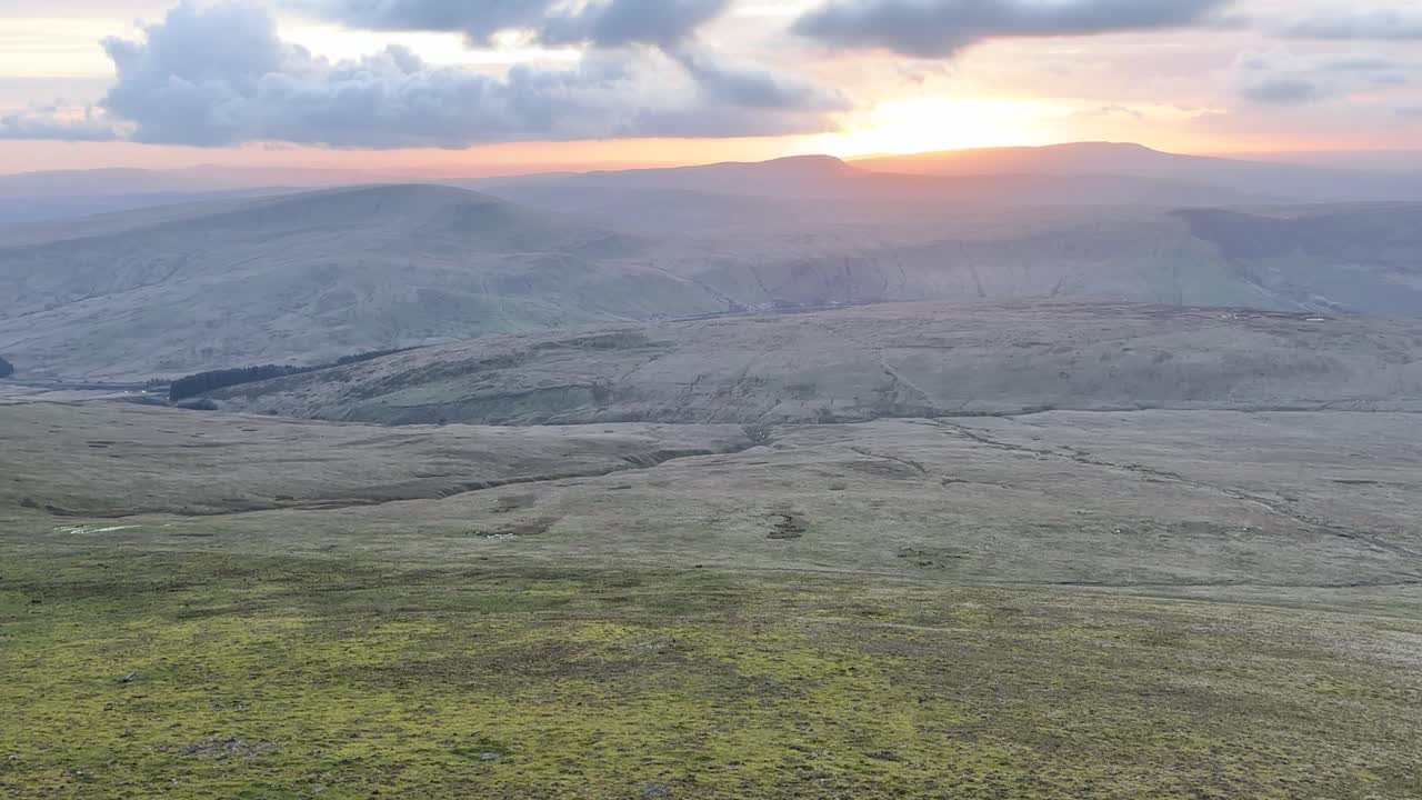 Ampie colline ondulate a Brecon Beacons con la luce del tramonto che si diffonde tra le valli sotto nuvole stratificate, creando un drammatico paesaggio montano con un'atmosfera naturale e calma.
