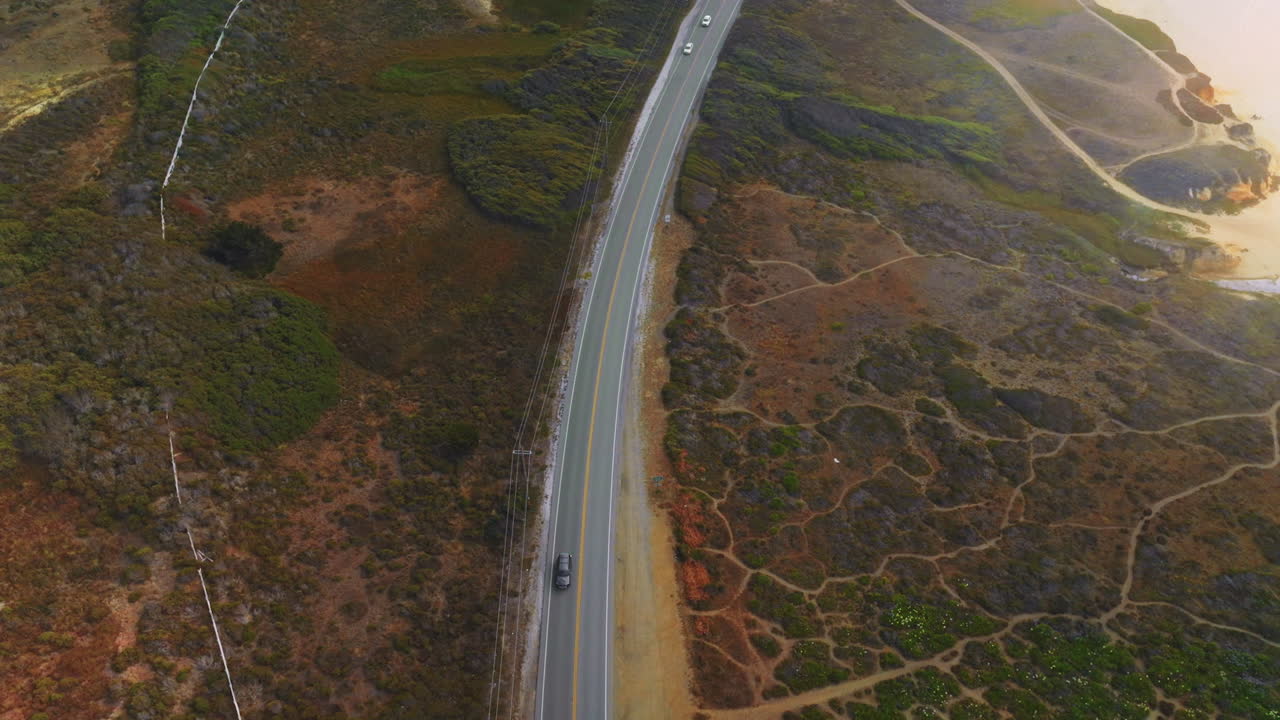 Motorway going through the dry rocky landscape. Drone descending over the highway with cars quickly moving by.