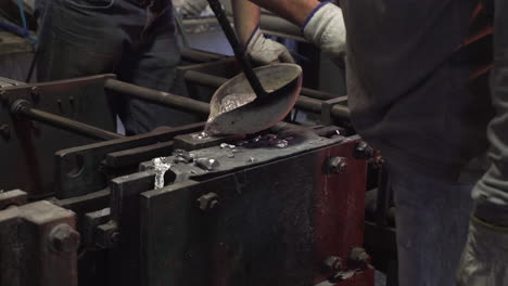 people pouring melted metal into casts in a factory