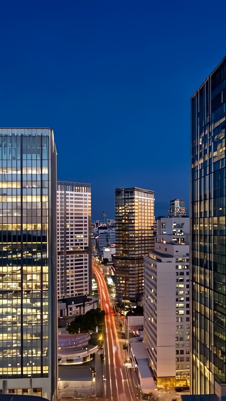 Vertical video: Watching light trails growing on avenue at dusk on balcony rail, with windows aglow