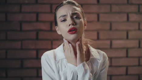 unhappy woman feeling sore throat and coughing on brick wall background