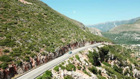 Albania,-aerial-view-from-a-drone-of-cars-driving-on-a-beautiful-yet-treacherous-road-along-a-steep-mountain-slope