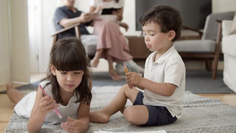 sweet little boy and girl with markers drawing in living room