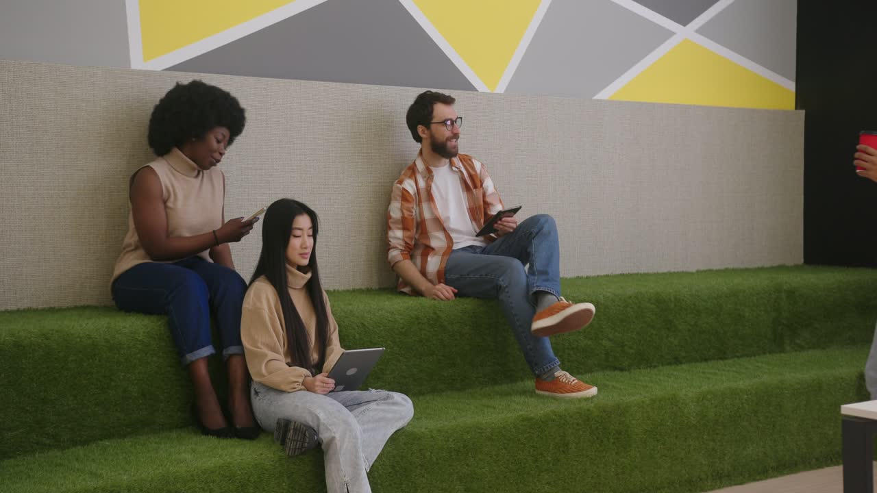 empleados multiculturales usan aparatos sentados en escalones verdes