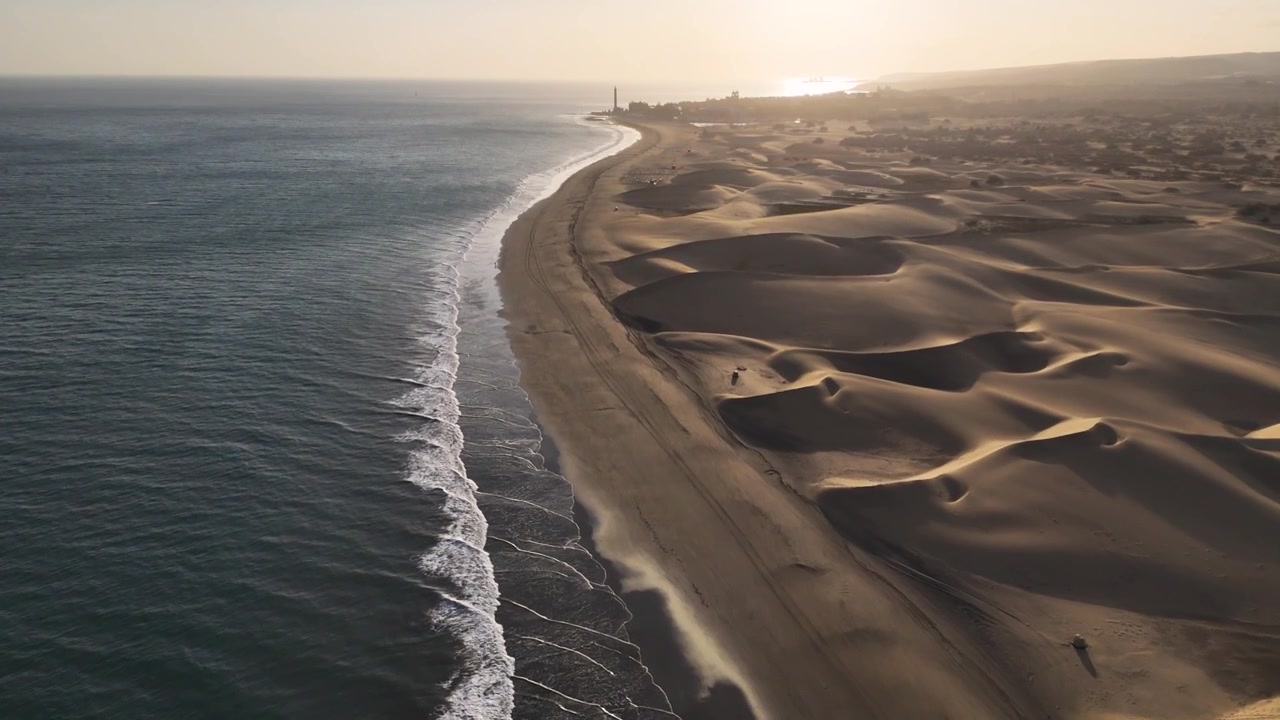 Maspalomas dunes follow the Atlantic shoreline in warm evening light on Gran Canaria, aerial