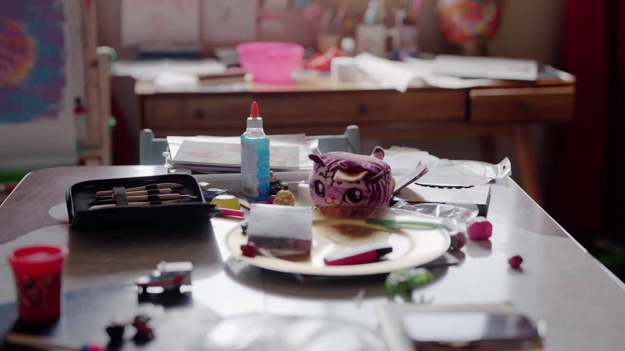 A kitchen table is covered with various arts and crafts items, including sculpting tools, toys and paint.