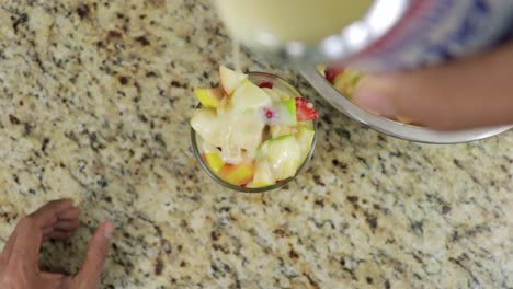 top view of adding condensed milk to fruit cocktail