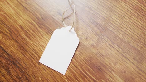 video of white gift tag with copy space and string on wooden background