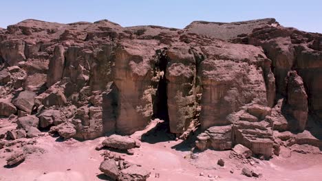 aerial slow and calming backward drone shot of a ridge in the middle of a desert, surrounded by boulders, sand and dirt