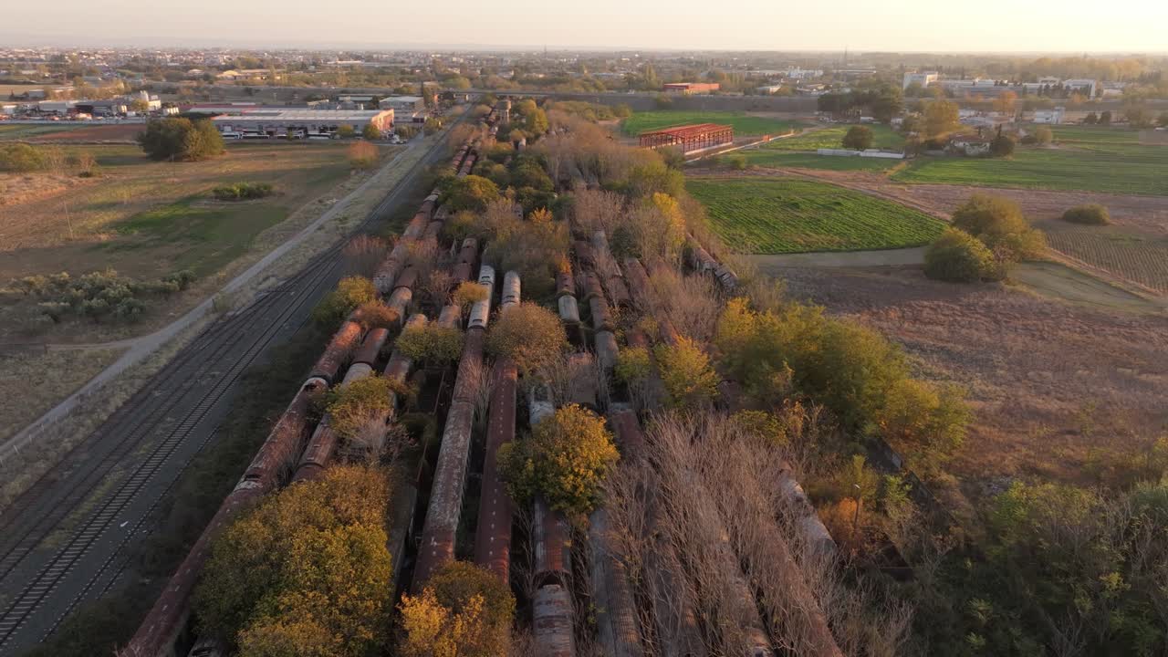 Vista dall'alto di un deposito ferroviario arrugginito immerso nella luce dell'ora d'oro, Grecia